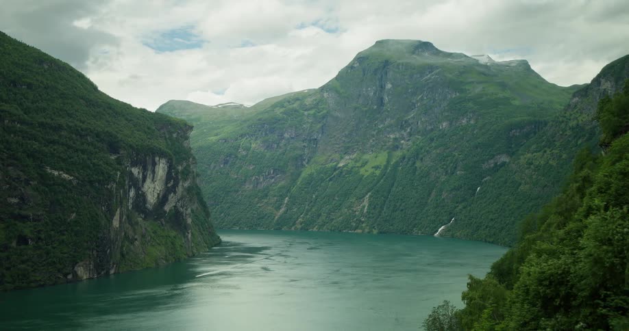 A river in between mountain covered in green grasses and vegetation