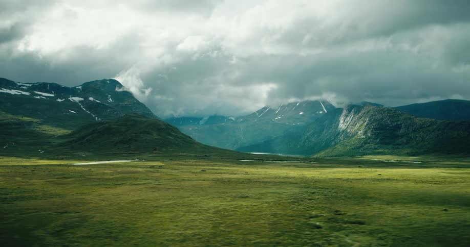 Landscape of grassland and distant mountains under clouds