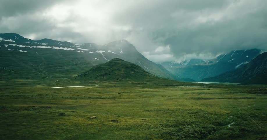 Landscape with vegetation lake and some mountains at cloud level with snow