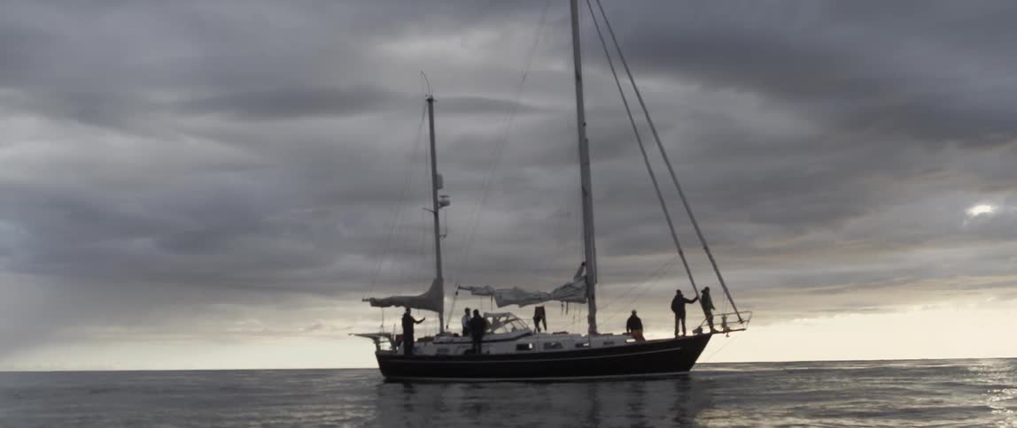 There are people on the boat and the sails are down