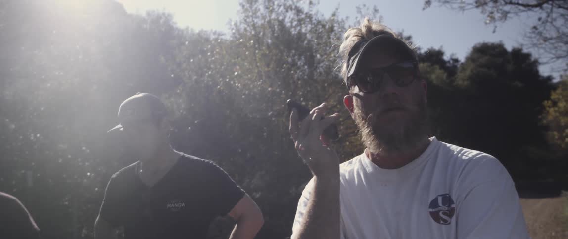 A man is holding a phone talking on a sunny day