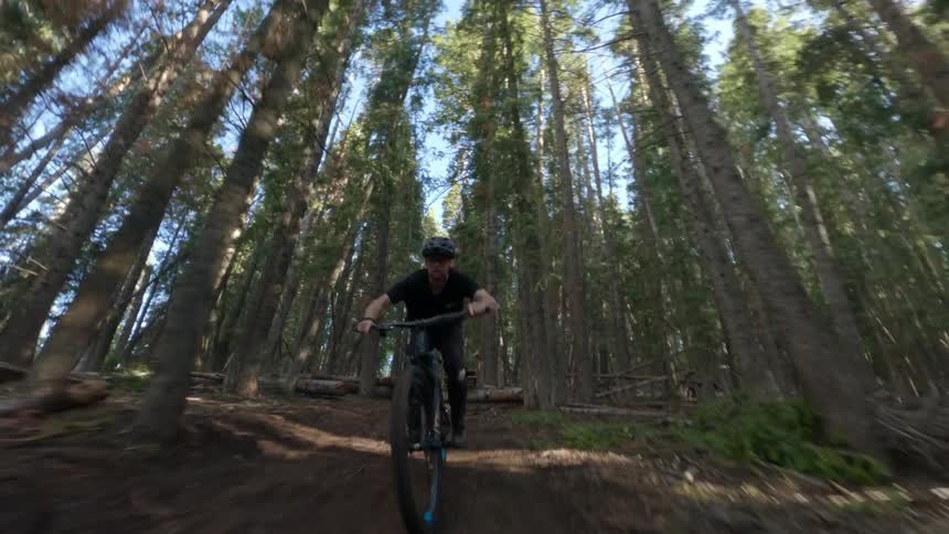 A man is riding his bike through the forest