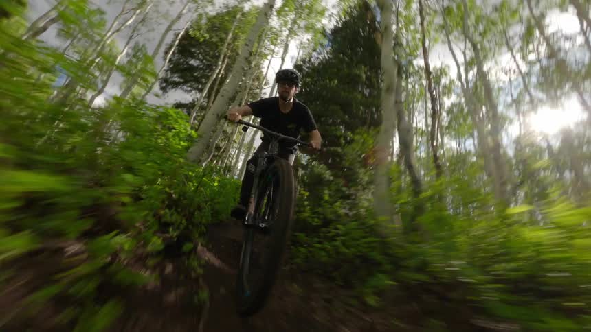 A man cycling down a hill in the middle of the forest