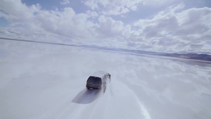 FPV drone footage of a pickup truck racing across the flooded Bonneville Salt Flats in Utah