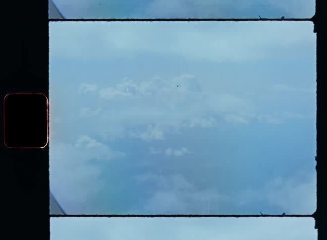 Film footage of flying through the cloud cover or layer viewed out of the window of a passenger flight or aircraft while cumulus clouds hover in the atmosphere during midday
