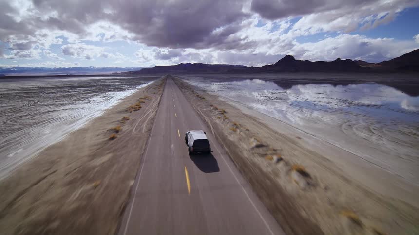 A truck speeds along a deserted road in a natural landscape, FPV drone footage