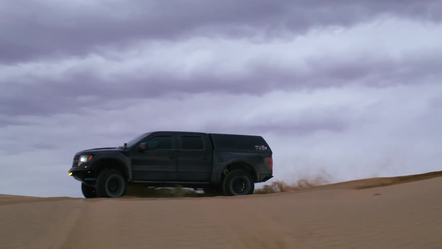 An all terrain pick up truck on a sand dune in the desert