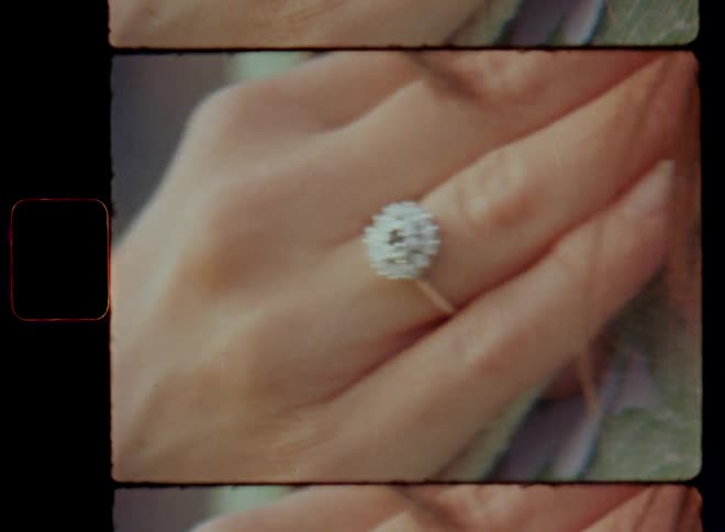 Super 8mm close up of the hand of a young woman with long brown hair placed on her chest with a silver jewelry diamond wedding or engagement ring on her ring finger after getting engaged with the love of her life on a romantic Valentine’s Day date
