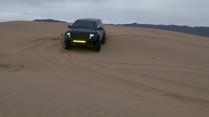Black pickup truck rallying on a sand dune