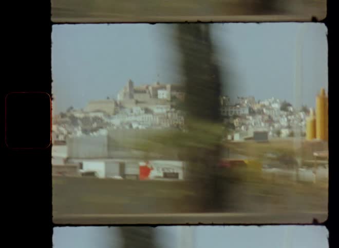 Dynamic view from the inside of a car driving on a motorway or highway with fast speed and movement onto city or town placed on a hill next to the road with industrial and factory buildings and a castle in the background