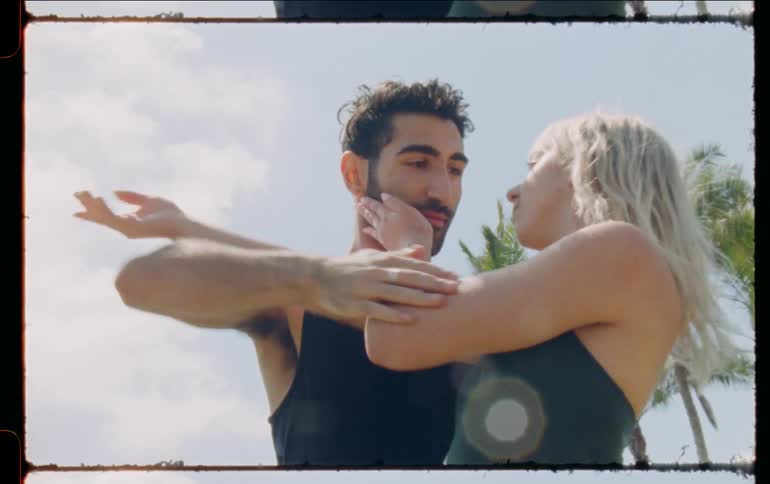Young couple touch each other while dancing outdoors caught on vintage film