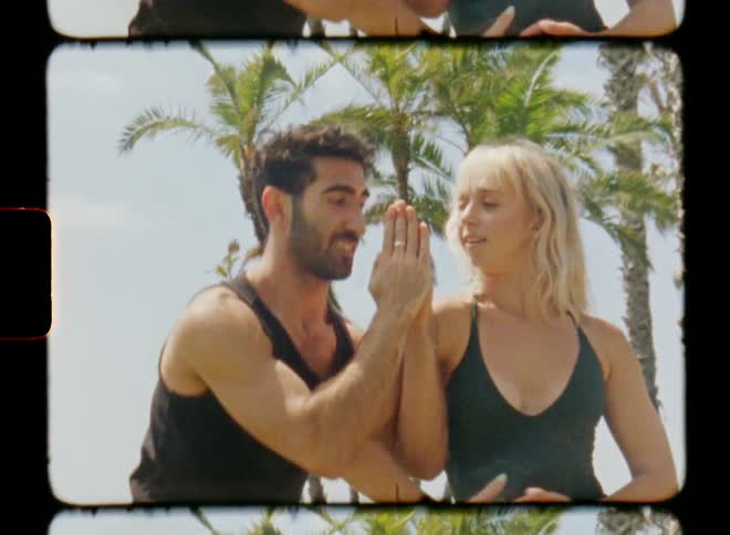 Two dancers perform routine with several hand gestures near palm trees