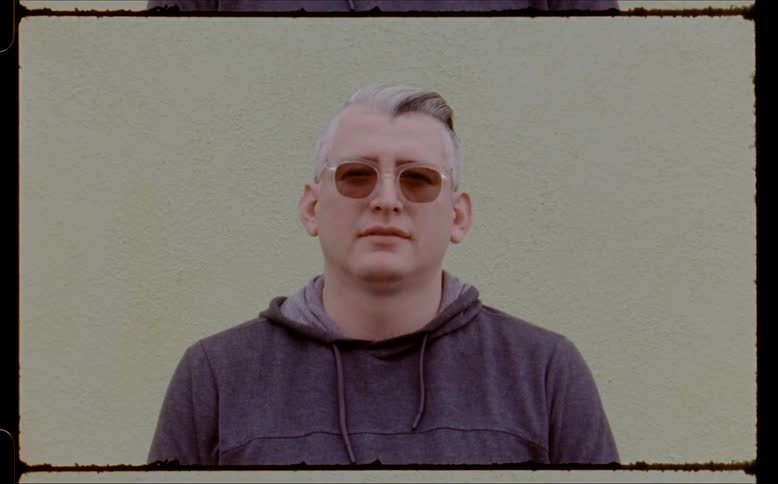 A man with white hair and wearing glasses staring straight ahead