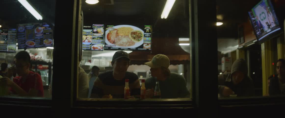 People sitting in a cafe at night talk and eat