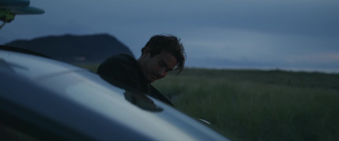 Two adults are getting into a vehicle parked in a flat grassy field