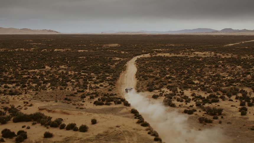 A truck speeds on a dirt road in the wilderness, cinema drone footage