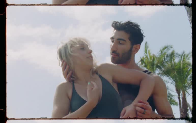 Man and woman dance slowly wrapping their arms over each others heads on cloudy day