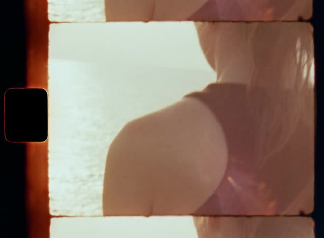 Close up of the backside of a woman sitting near the ocean meditating as the sun sets on the horizon and she is contemplating and clearing her mind to connect with herself and nature in a peaceful spiritual experience with thankfulness