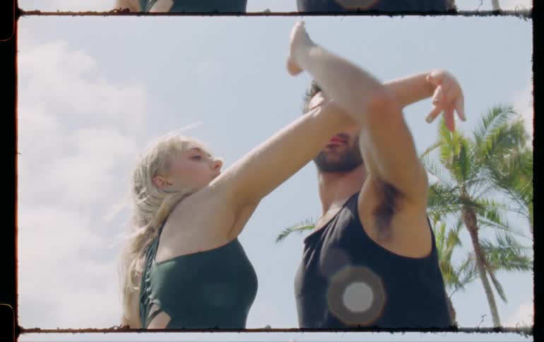 Man and woman are dancing together outdoors on a sunny day