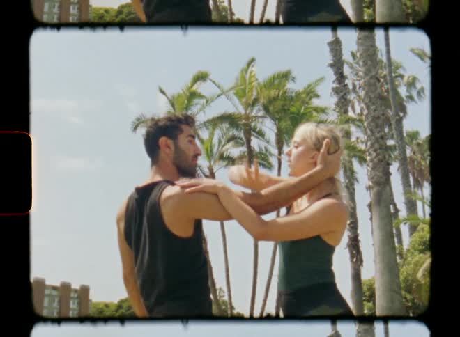A man and a woman dancing a choreography with physical contact in an outdoor environment with vegetation