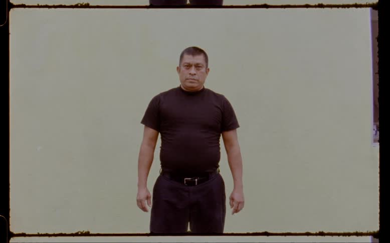 Film footage of a man standing in front of a walll