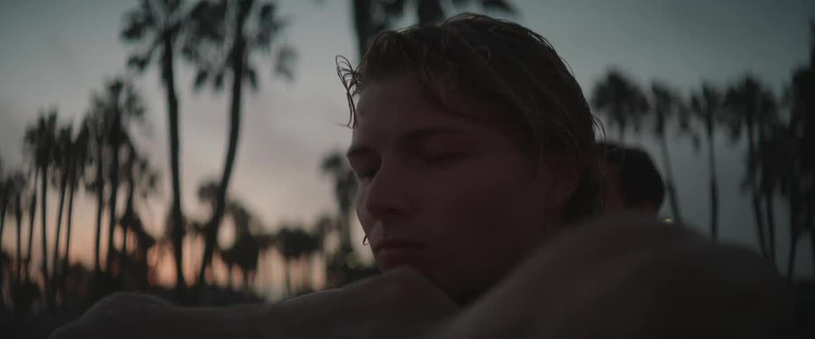 A man with wet hair looks straight ahead and puts his head in his arms