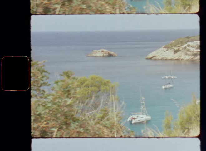 Various sail boats or motor boats or sailing yachts anchored near a coastline in a quiet idyllic bay protected from the open ocean reminiscent of the Caribbean Sea with rock cliffs on a bright sunny day with sun shine and warm weather