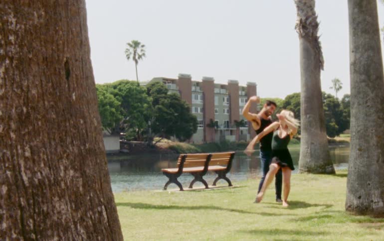 Man and woman are dancing together at a park during spring