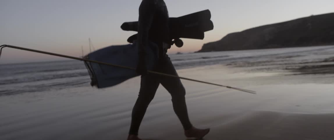 A man is walking on the beach at dawn
