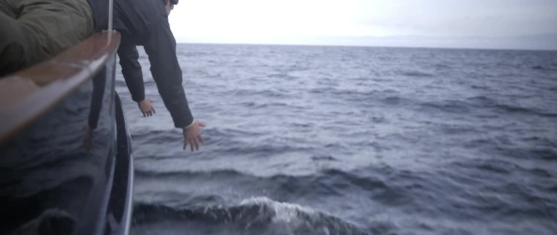 A person leans overboard on a ship with his hands down