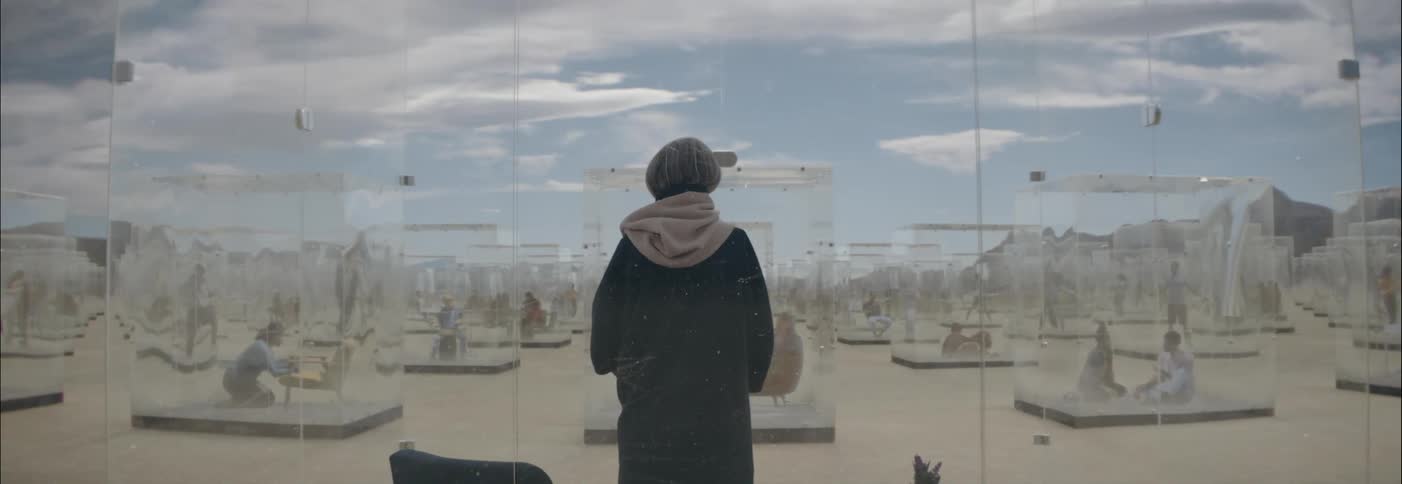 People trapped inside glass cubes in the desert going about their lives