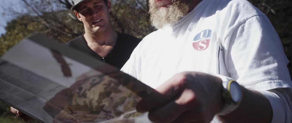 Two men look at a map on a sunny day