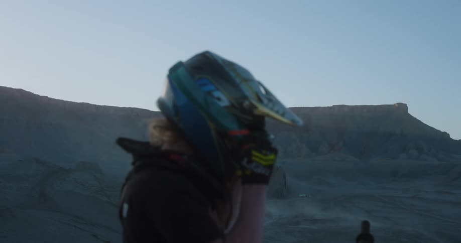 A man takes off his helmet on his dirt bike