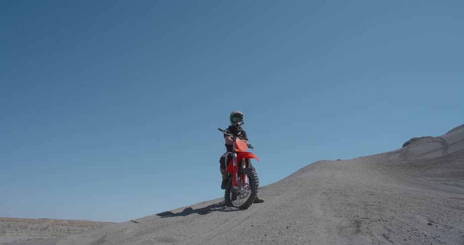 A motorcycle and its rider standing still in the desert