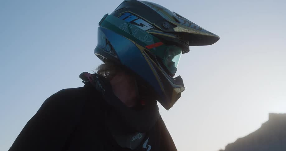 Young man wearing a crash helmet sits on a motorcycle outdoors