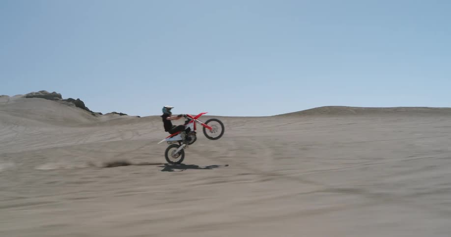 A motorcyclist performs a dangerous maneuver in a deserted landscape