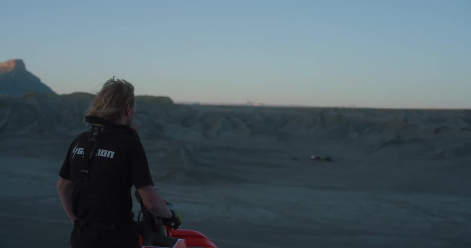 Man sit on a motorcycle deep in thought in a desert area at sunset