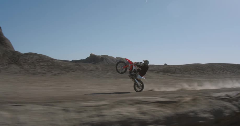 A man is doing a wheelie on his dirt bike
