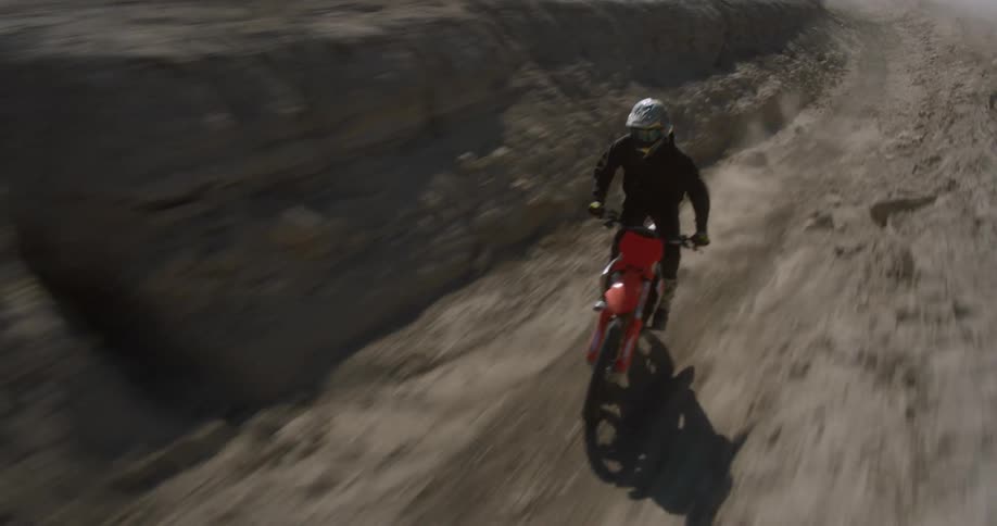 A person riding a trail bike through a desert region quickly