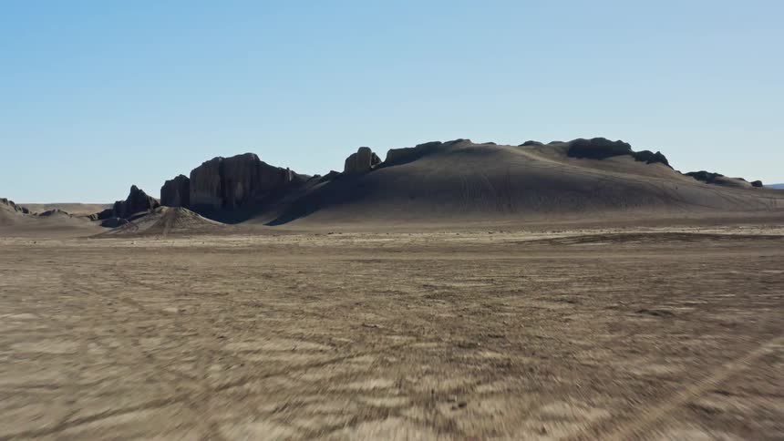 A deserted field and in the background there are sand and stone hills