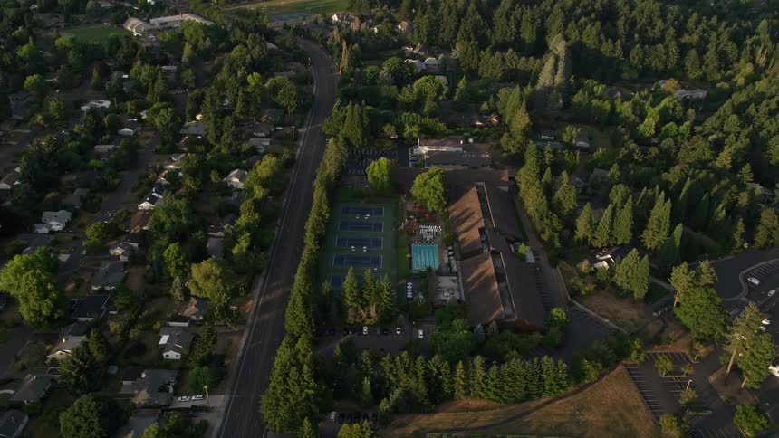 Aerial view of a community sports center in Beaverton Oregon during sunset showcasing tennis courts and pools with a partially cloudy sky in the background
