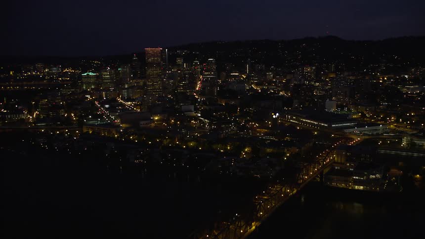 Approaching Steel Bridge at night revealing downtown Portland's illuminated skyscrapers and cityscape over the Willamette River