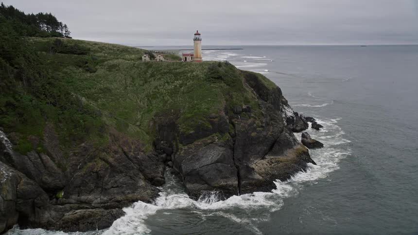 Aerial view of North Head Light atop a green cliff overlooking the Pacific Ocean in Ilwaco Washington during a sunny summer day