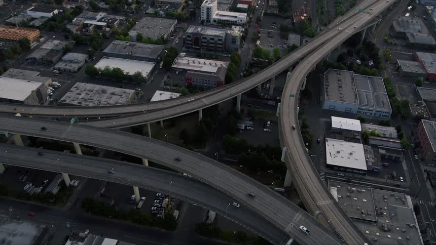 Tilting down from a bird's eye view this aerial footage captures the Highway 30 and Interstate 405 interchange in Portland Oregon during sunset showcasing the bustling metropolis below