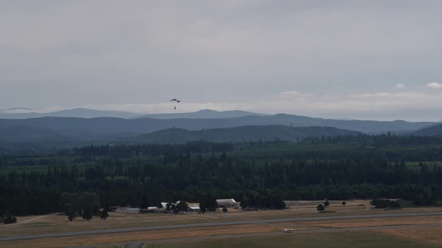 A skydiver gracefully lands at Sanderson Field airport in Shelton Washington during a sunny summer day
