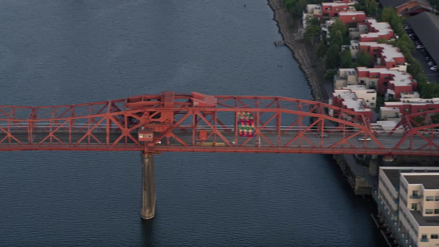 Aerial footage tracking a white car crossing Broadway Bridge into Downtown Portland during sunset showcasing the metropolis and city river