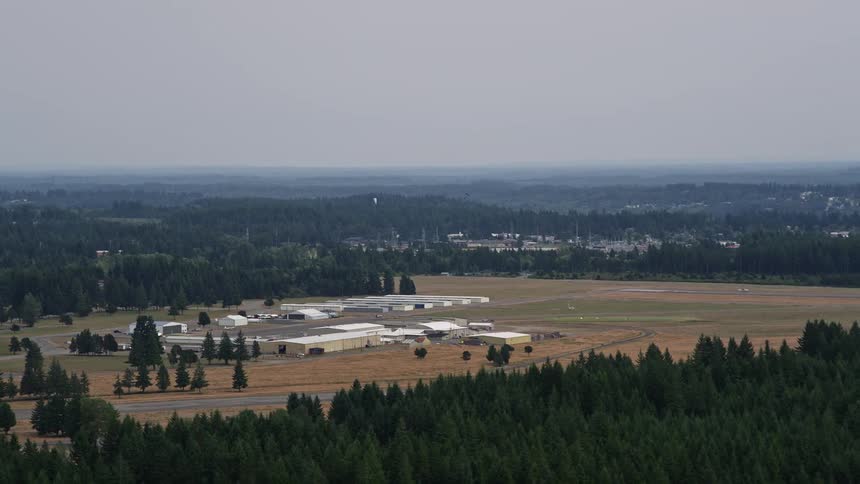 Aerial footage of Sanderson Field airport hangars in Shelton Washington showcasing the corporate areas surrounded by natural spaces like forests during daytime in summer