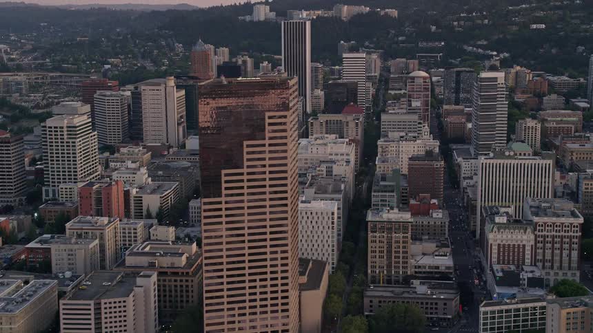 Aerial footage of downtown Portland Oregon at sunset flying by US Bancorp Tower and city streets