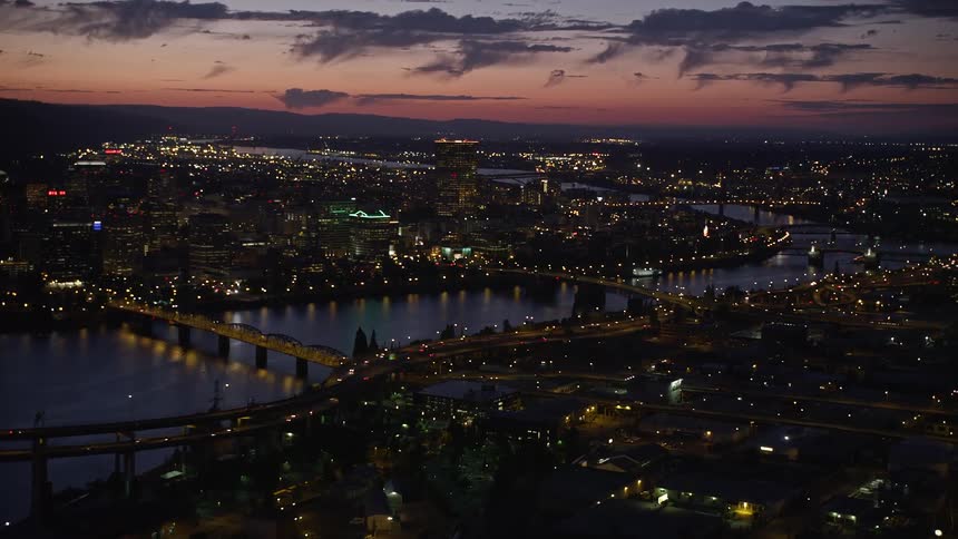an aerial view of Downtown Portland Oregon at twilight capturing the city skyline the Willamette River and the Morrison Bridge with city lights illuminating the night