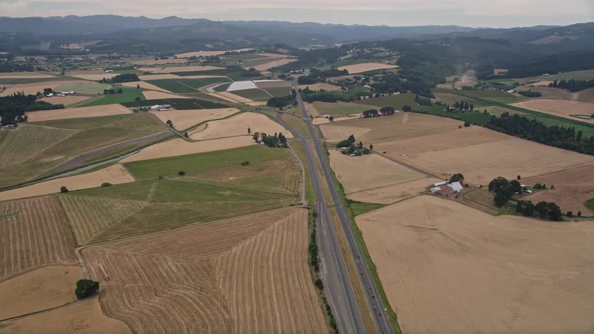 Aerial view of a highway cutting through a rural landscape with vast fields and open grassland in Banks Oregon during summer